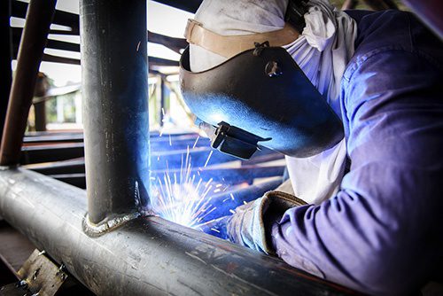 Welder working on steel structure on site.