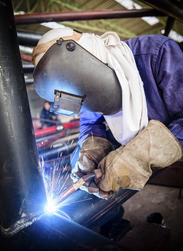 Welder working on join in fabrication shop.