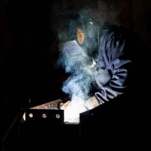 Skilled welder working in the dark on a welding project.